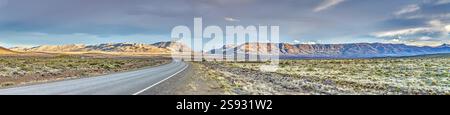Panoramablick auf eine Straße, die durch die riesige argentinische Steppe in Patagonien führt, mit goldenem Licht während des Tages Stockfoto