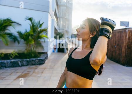 Eine Frau dehnt ihren Arm, während sie einen schwarzen Sport-BH trägt. Konzept der Entschlossenheit und Konzentration bei der Vorbereitung der Frau auf ihr Training Stockfoto