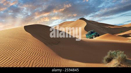 Land Riover Defender Fahrt durch die wunderschönen Erg Chebbi Saharah Sanddünen, Sahara, Marokko bei Sonnenaufgang Panoramablick Stockfoto