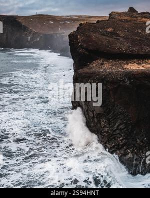 Dramatische Meereswellen krachen gegen die Basaltklippen von Dyrhólaey, Süd-Island. Stockfoto