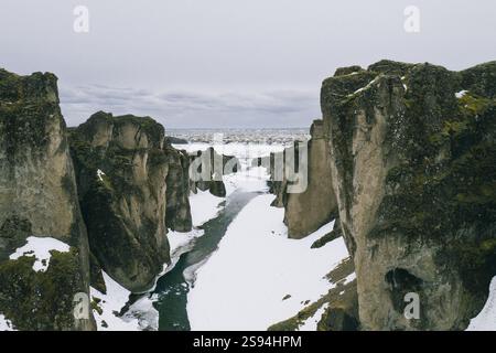 Schneebedeckter Fjaðrárgljúfur Canyon mit einem sich windenden Fluss, Südisland. Stockfoto