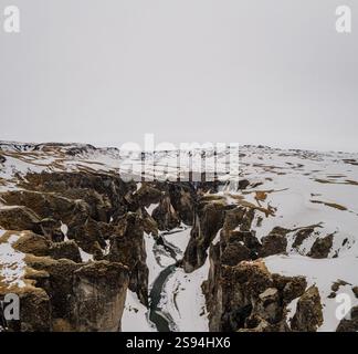 Schneebedeckter Fjaðrárgljúfur Canyon mit einem sich windenden Fluss, Südisland. Stockfoto