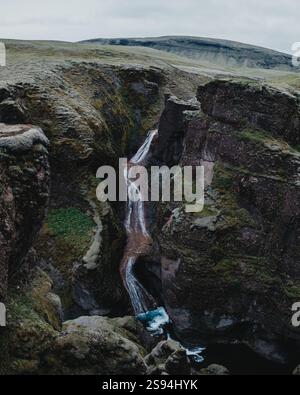 Moosbedeckter Mogafoss-Wasserfall, der durch zerklüftete Klippen in Südisland kaskadiert. Stockfoto