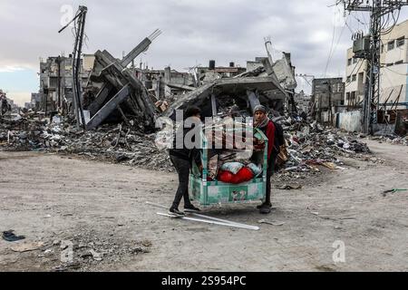 Rafah, Palästina. Januar 2025. 24. Januar 2025, Palästinensische Gebiete, Rafah: Die Palästinenser tragen ihre Sachen, während sie an zerstörten Häusern im Shaboura-Gebiet im Zentrum der Stadt Rafah entlang laufen, Tage nach Inkrafttreten des Waffenstillstandsabkommens zwischen Israel und Hamas. Foto: Abed Rahim Khatib/dpa Credit: dpa Picture Alliance/Alamy Live News Stockfoto