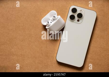 Ukraine Dnipro 24. Januar 2025 - Apple iPhone 15 Pro Max weiß und Apple Air Pods 4 mit Kopfhörern auf braunem Papier Stockfoto