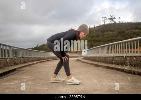 Joggerin, die ihr Knie schmerzhaft hält Stockfoto