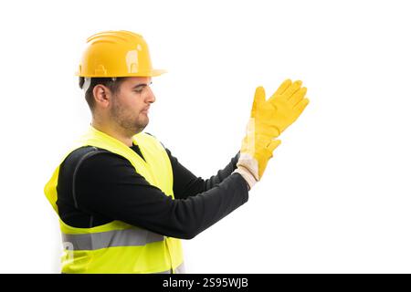 Bauarbeiter tragen Schutzhelm und fluoreszierende Weste, ziehen gelbe Industriehandschuhe als betriebsbereites Konzept mit Copyspace an Stockfoto