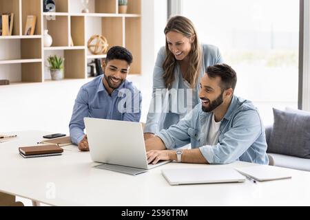 Drei multiethnische Kollegen arbeiten mit einem Laptop zusammen Stockfoto
