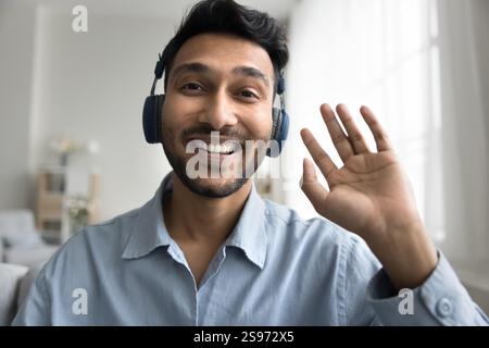 Lächelnder Millennial männlicher in Ohrhörern Aufnahme Video Wave Hand Hi Stockfoto