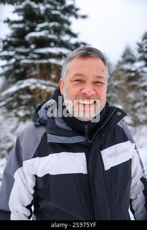 Ein 50-jähriger Mann spaziert draußen in einem Winterwald Stockfoto