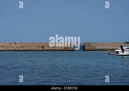 Chania - Kreta - 17. August 2024; Menschen auf einem Wellengang über den Hafen an einem wunderschönen mediterranen Tag. Stockfoto
