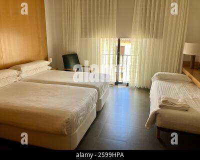Hotelzimmer: Dreibettzimmer, Jalousien und Vorhänge gezogen, bereit für Gäste Stockfoto