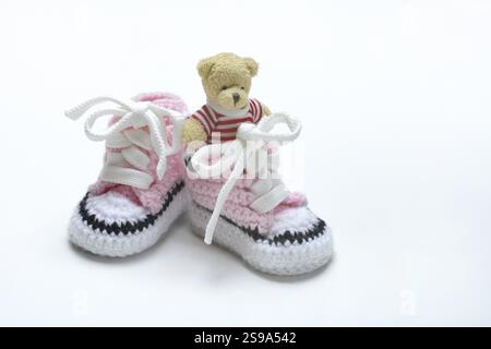 Babyschuhe und Teddybär, weißer Hintergrund Stockfoto