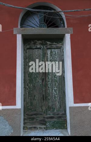Alte, grün lackierte Holzeingangstür auf rotbraunem Braun mit weißer Stuckfassade, Riomaggiore, Cinque Terre, La S Stockfoto