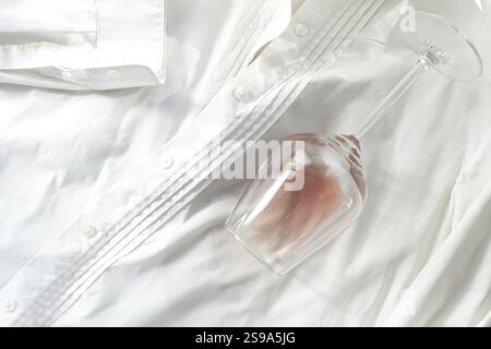 Glas, mit rosafarbenem Wein, verschüttet auf einem weißen Hemd, Nahaufnahme, selektiver Fokus, keine Leute, Konzept, Draufsicht Stockfoto
