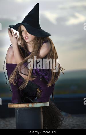 Hübsche Hexe mit Hut und Besen, draußen Stockfoto