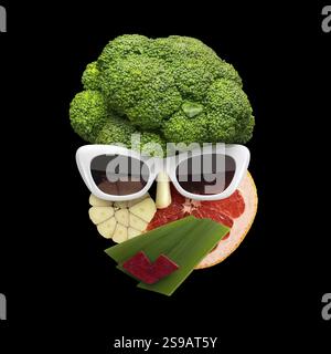 Skurriles Lebensmittelkonzept des kubistischen weiblichen Gesichts in Sonnenbrille aus Obst und Gemüse, auf schwarzem Hintergrund Stockfoto