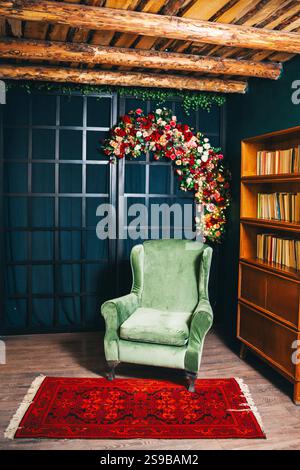 Grüner Sessel vor einem schwarzen Gitter mit Blumen. Fotobereich mit weichem Sessel Stockfoto
