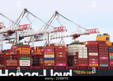 Eine Nahaufnahme des Daches eines großen Frachtschiffes, das in einem britischen Hafen angedockt ist und mit Frachtcontainern beladen wird, die von Kränen gestapelt werden Stockfoto