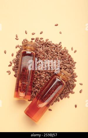 Leinsamen mit Leinsamenöl in Glasflasche auf beigem Hintergrund. Draufsicht. Stockfoto