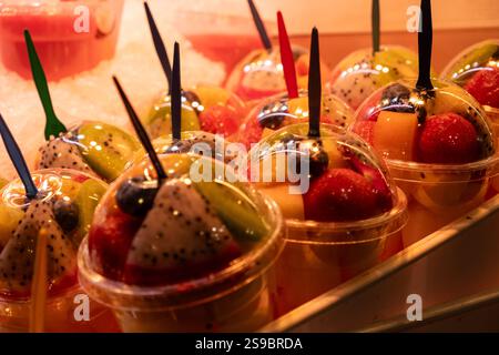 Mehrere Gläser Obstsalat warten im Fenster eines kleinen Unternehmens. Das Licht ist warm und die Vielfalt der Früchte überflutet das Bild mit Farbe. Essen und Stockfoto