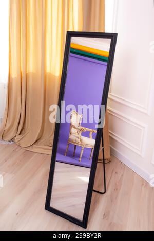 Reflexion von Holzstuhl auf farbigem Hintergrund im Spiegel. Fotobereich mit farbigem Hintergrund Stockfoto