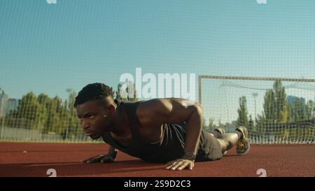 Sportlicher Bodybuilder afroamerikanischer Sportler junger Mann, der Liegestützübungen auf Fußballstadion macht männliche starke Athlet Fitness Training Muskeln Stockfoto