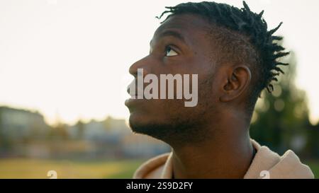 Outdoor Nahaufnahme männliches Gesicht afroamerikanischer ethnischer Sport Mann nachdenklich verärgert traurig frustrierter Kerl, der in Sonnenstrahl aufblickt Relax Traum Ruhe danach Stockfoto