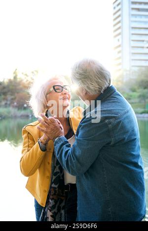 Fröhliche, reife Erwachsene Ehe feiern mit Tanz und Händen in der Mitte der Lake Park City Stockfoto