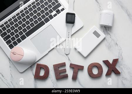 Set aus modernen Gadgets und WORTENTGIFTUNG aus Holzbuchstaben auf hellem Hintergrund Stockfoto