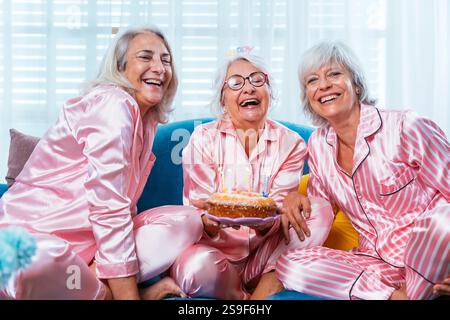 Schöne ältere Frauen, die zu Hause eine lustige Pyjama-Party haben - Gruppe von fröhlichen älteren weiblichen Freunden, die zu Hause Spaß haben und Geburtstag feiern, Conce Stockfoto