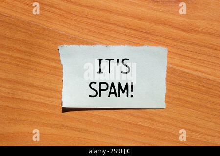 Es ist eine Spam-Nachricht, geschrieben auf zerrissenem Papierstück mit hölzernem Hintergrund. Konzeptionell ist das Spam-Symbol. Kopierbereich. Stockfoto