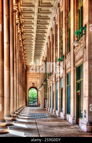 Ein atemberaubender Korridor mit Pracht und Symmetrie, eingerahmt von hohen Säulen und komplexen architektonischen Details. Diese historische Struktur strahlt ein s aus Stockfoto