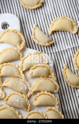 Frische, hausgemachte Teigtaschen, zubereitet auf einem Marmorbrett, mit traditioneller handgefertigter Handwerkskunst. Roher Teig gefüllt mit herzhaften Zutaten, fertig für Stockfoto