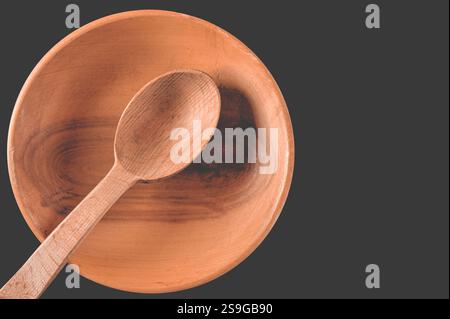 Brauner Holzlöffel in Holzteller auf schwarzem Tisch Stockfoto