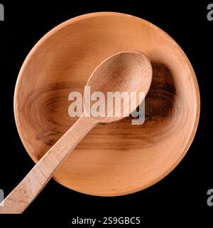 Brauner Holzlöffel in Holzteller auf schwarzem Tisch Stockfoto