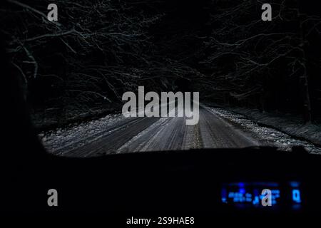 Auto Cockpit Blick auf Nachtwagen, der im Winterwald fährt Stockfoto