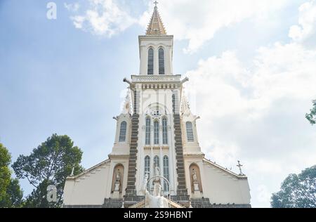Ho-Chi-Minh-Stadt, Vietnam - 02.07.2023: Eine majestätische weiße Kirche mit einem Kirchturm steht zwischen Bäumen und sonnt sich bei Tageslicht Stockfoto