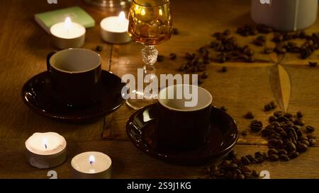 Zwei Mokkatassen, Teelichter, Kaffeebohnen, ein Likörglas. Stockfoto
