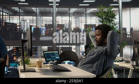 Ein gestresster afroamerikanischer Geschäftsmann macht eine Pause von seinen Büroaufgaben, fühlt sich unter Druck und arbeitet hart an einem neuen Projekt. Unternehmensmitarbeiter versucht, eine Frist einzuhalten. Kamera B.. Stockfoto
