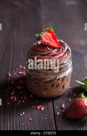 Köstliches Schokoladenmousse mit frischen und gefriergetrockneten Erdbeeren in Glasgläsern Stockfoto