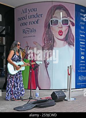 Eine Buskerin mit einer hellblauen Fender-Akustikgitarre vor dem Royals Shopping Centre in der High Street in Southend on Sea. Stockfoto