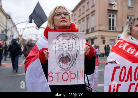 Warschau, Polen. Januar 2025. Eine Frau, die in eine historische belarussische Flagge gehüllt ist, hält ein Plakat mit dem Bild von Alexander Lukaschenko, der blutig ist und den Buchstaben Z auf der Stirn trägt, während sie am Marsch der belarussischen Menschen teilnimmt. Viele Weißrussen auf der ganzen Welt kamen zusammen, um gegen die Präsidentschaftswahlen in Belarus zu protestieren. Alexander Lukaschenko, der das Amt seit 1994 innehat, sucht eine siebte Amtszeit. Quelle: SOPA Images Limited/Alamy Live News Stockfoto