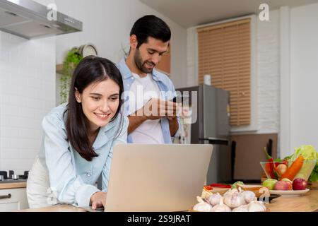 Wir haben definitiv etwas gespart. Foto von einem Paar, das zusammen zu Hause Papierkram durchsucht. Glückliche Frau, die einen neuen Laptop aufbaut. Ehemann und Ehefrau Stockfoto
