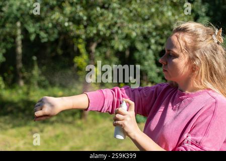Frau, die Insektenschutzmittel aufträgt, um Fliegen, Wanzen und Mücken auf der Haut draußen zu töten. Malaria-zika-Virus und Denguefieberprophylaxe. Schutzmaßnahmen Stockfoto
