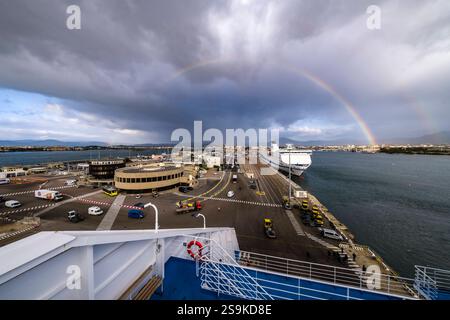 Blick von einer Fähre auf den Hafen von Olbia, ein Regenbogen erstreckt sich über die Häuser der Stadt in der Ferne. Olbia Sardinien Italien FB 2024 1222 Stockfoto