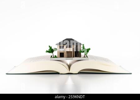 Offenes Buch und Miniatur-Einfamilienhaus Stockfoto