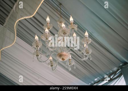 Eleganter Kronleuchter, der an einer drapierten Decke hängt. Stockfoto