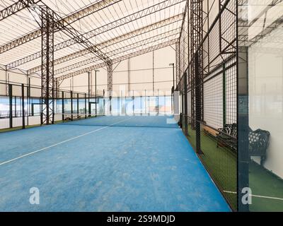 Leerer Paddle-Tennisplatz mit Lichtern in einem überdachten Schuppen ohne Spieler. Hochwertige Fotos Stockfoto