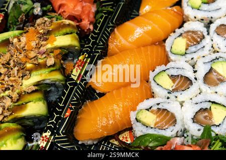 Köstliches japanisches Sushi - Lachsnigiri, kalifornische Rolle und Drachenrolle auf Plastiktabletts Stockfoto